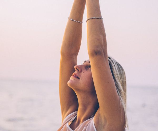 Person meditating peacefully outdoors during sunrise.